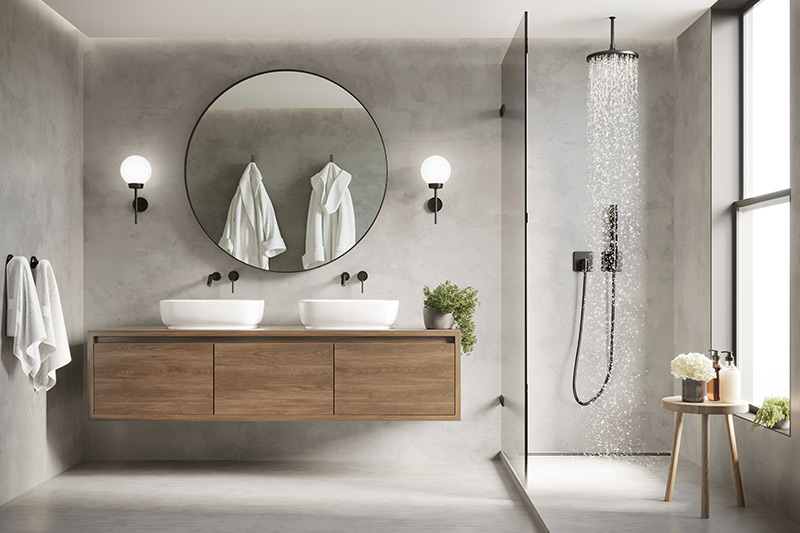 Modern bathroom with round mirror, dual sinks, and rainfall shower in a glass enclosure.